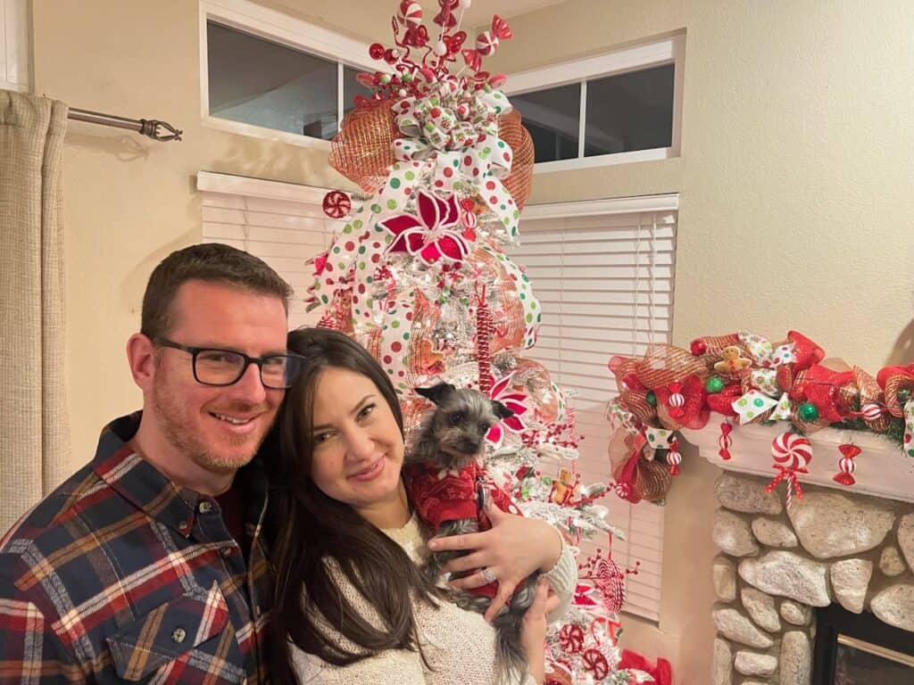 beau mcfarland and his wife and dog, standing in front of a red and white christmas tree in their home in chino